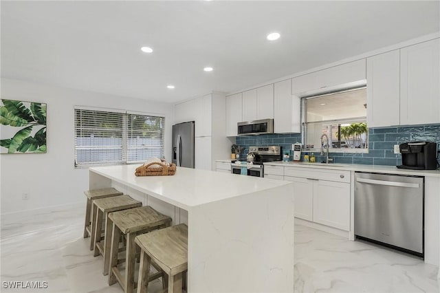 5127 SW 3rd Ave, Cape Coral, FL 33914 - kitchen with stainless steel appliances, a sink, light marble finish flooring, a center island, and decorative backsplash