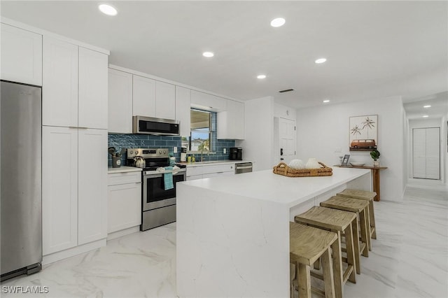 5127 SW 3rd Ave, Cape Coral, FL 33914 - kitchen with stainless steel appliances, a center island, decorative backsplash, a kitchen bar, and recessed lighting