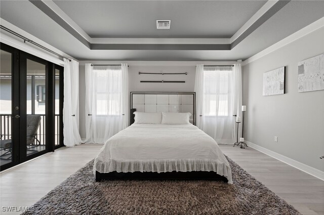 4654 Kensington Cir, Naples, FL 34119 - bedroom featuring french doors, a tray ceiling, access to exterior, and light wood finished floors