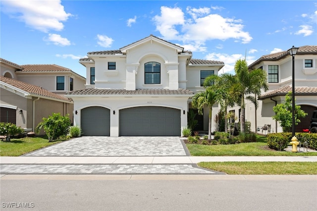 4654 Kensington Cir, Naples, FL 34119 - mediterranean / spanish-style home featuring an attached garage, a tiled roof, stucco siding, and decorative driveway
