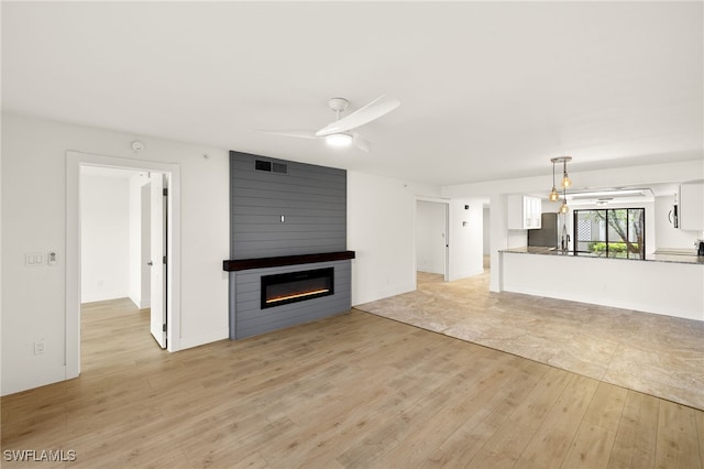 16290 Kelly Cove Dr Unit 253, Fort Myers, FL 33908 - unfurnished living room featuring light wood-style floors, a large fireplace, a ceiling fan, and a sink