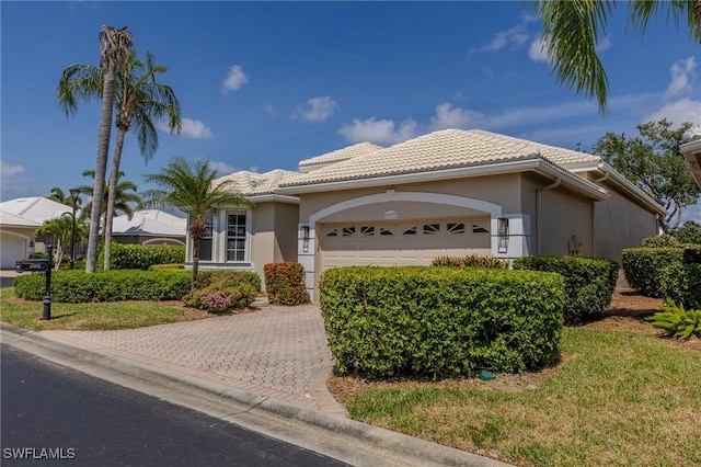 19372 Silver Oak Dr, Estero, FL 33967 - view of front of house featuring an attached garage, a tiled roof, stucco siding, and driveway