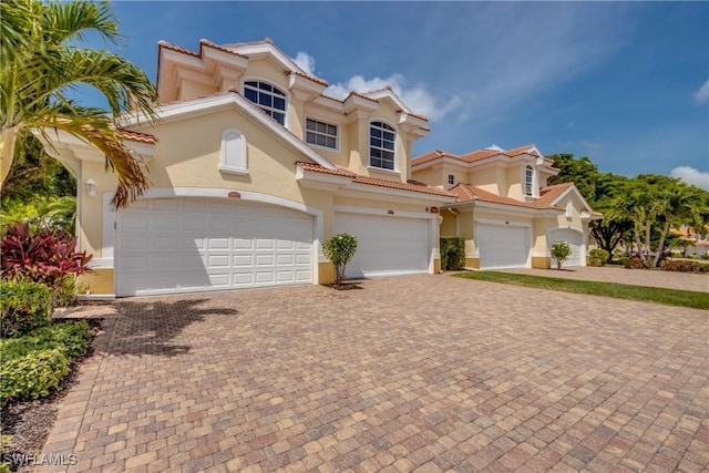 5912 Tarpon Gardens Cir Unit 201, Cape Coral, FL 33914 - view of front of property with stucco siding, decorative driveway, a tile roof, and an attached garage