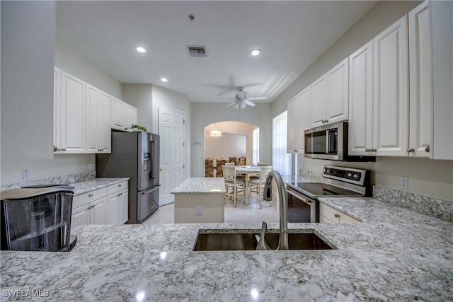 5912 Tarpon Gardens Cir Unit 201, Cape Coral, FL 33914 - kitchen featuring stainless steel appliances, a sink, light stone countertops, arched walkways, and recessed lighting