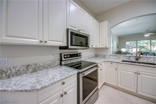 5912 Tarpon Gardens Cir Unit 201, Cape Coral, FL 33914 - kitchen with stainless steel appliances, a sink, arched walkways, white cabinets, and light tile patterned flooring