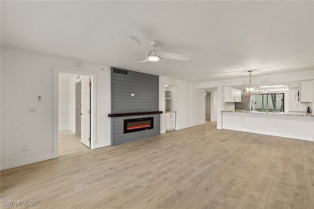 16410 Kelly Cove Dr Unit 313, Fort Myers, FL 33908 - unfurnished living room featuring a fireplace, light wood-style floors, a ceiling fan, a chandelier, and baseboards