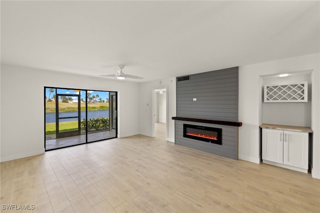 16410 Kelly Cove Dr Unit 313, Fort Myers, FL 33908 - unfurnished living room with a large fireplace, ceiling fan, baseboards, light wood-type flooring, and a water view