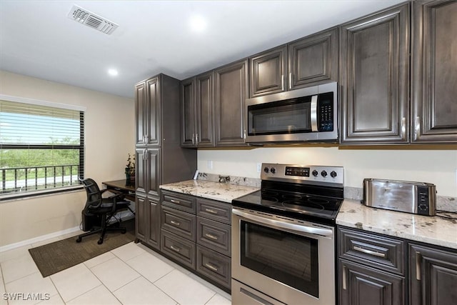 12581 Kelly Sands Way Unit 525, Fort Myers, FL 33908 - kitchen featuring appliances with stainless steel finishes, light tile patterned flooring, baseboards, light stone counters, and dark brown cabinets