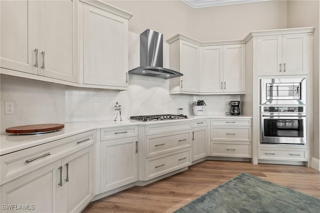 4324 SW 26th Ave, Cape Coral, FL 33914 - kitchen featuring stainless steel appliances, wall chimney range hood, light countertops, light wood finished floors, and ornamental molding