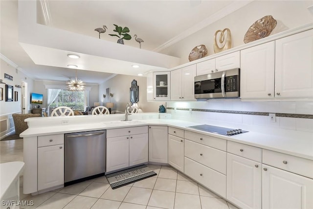 14550 Red Fox Run Unit 407, Naples, FL 34110 - kitchen featuring appliances with stainless steel finishes, a sink, crown molding, a peninsula, and white cabinets