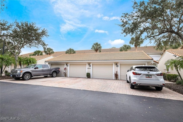 14550 Red Fox Run Unit 407, Naples, FL 34110 - view of front of house with community garages, a tiled roof, and stucco siding