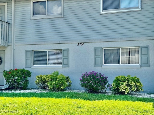 5751 Foxlake Dr Unit A, North Fort Myers, FL 33917 - view of property exterior with a lawn and stucco siding