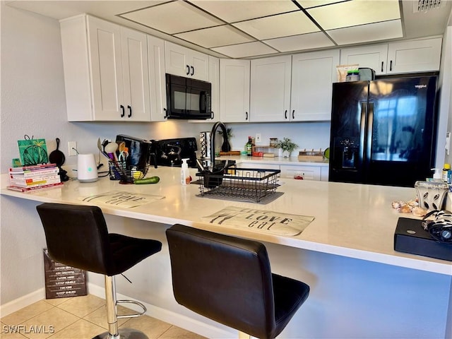 5751 Foxlake Dr Unit A, North Fort Myers, FL 33917 - kitchen featuring black appliances, a peninsula, a breakfast bar area, light countertops, and white cabinets
