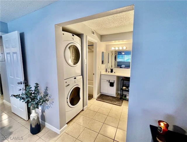 5751 Foxlake Dr Unit A, North Fort Myers, FL 33917 - laundry area with stacked washer / drying machine, a textured ceiling, light tile patterned floors, and baseboards