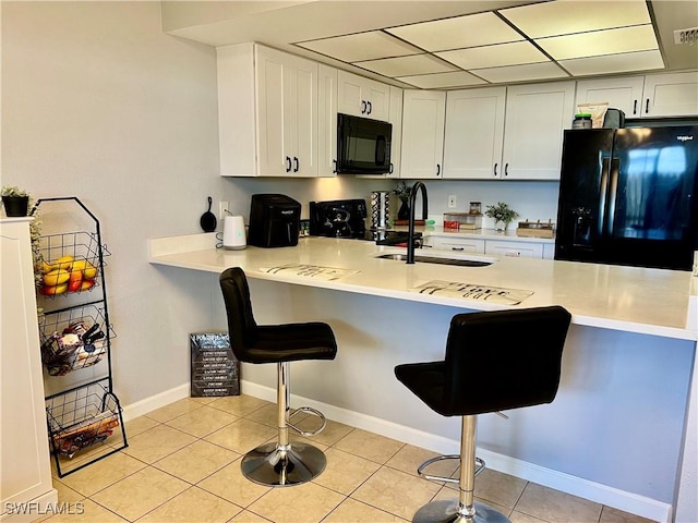 5751 Foxlake Dr Unit A, North Fort Myers, FL 33917 - kitchen featuring black appliances, a sink, a peninsula, a kitchen bar, and light tile patterned floors