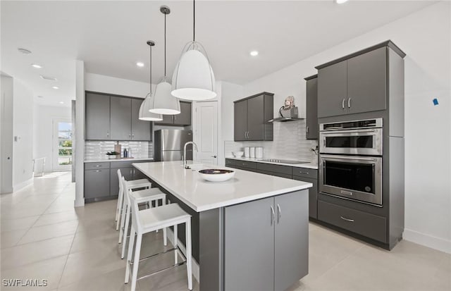 12412 Basalt Ln, Alva, FL 33982 - kitchen featuring appliances with stainless steel finishes, decorative backsplash, a kitchen bar, a sink, and pendant lighting