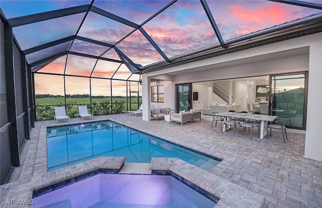 12412 Basalt Ln, Alva, FL 33982 - pool at dusk with an outdoor living space, a patio area, a lanai, and a pool with connected hot tub