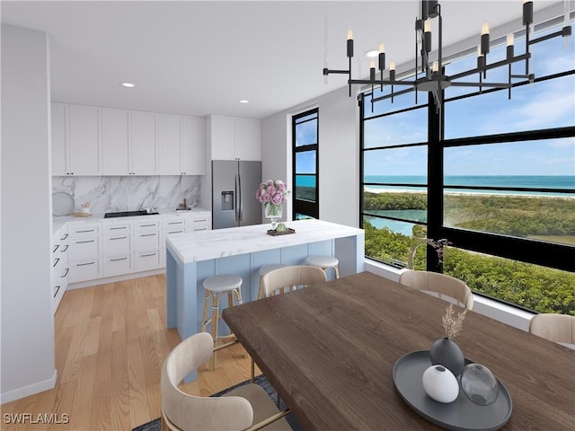 440 Seaview Ct Unit 1012, Marco Island, FL 34145 - kitchen featuring stainless steel fridge with ice dispenser, decorative backsplash, light wood-style flooring, a center island, and light countertops