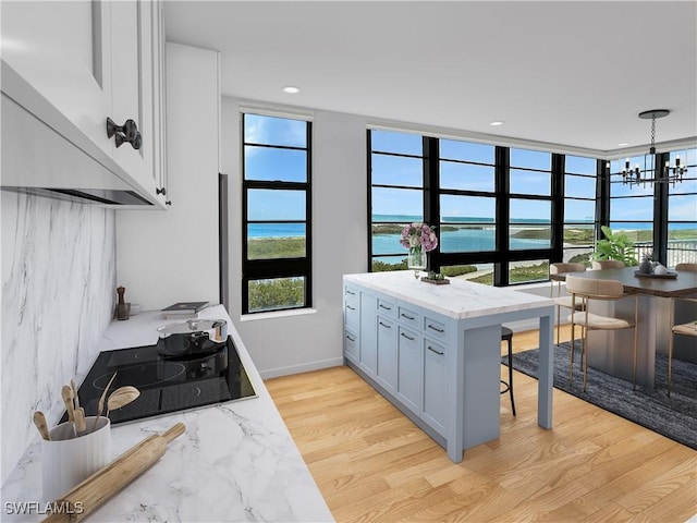 440 Seaview Ct Unit 1012, Marco Island, FL 34145 - kitchen featuring black electric cooktop, a chandelier, plenty of natural light, and light stone counters