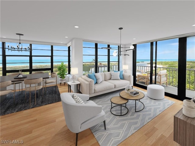 440 Seaview Ct Unit 1012, Marco Island, FL 34145 - living room featuring a wall of windows, a chandelier, light wood-type flooring, a water view, and plenty of natural light