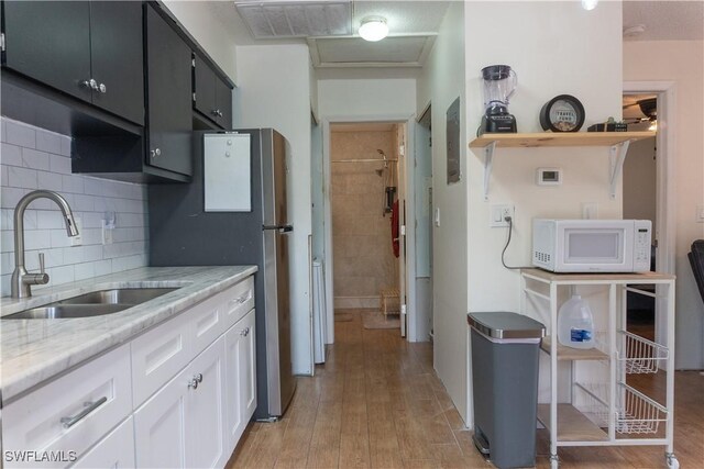1165 Palm Ave Unit 8A, North Fort Myers, FL 33903 - kitchen featuring a sink, white microwave, white cabinets, decorative backsplash, and light wood-style floors