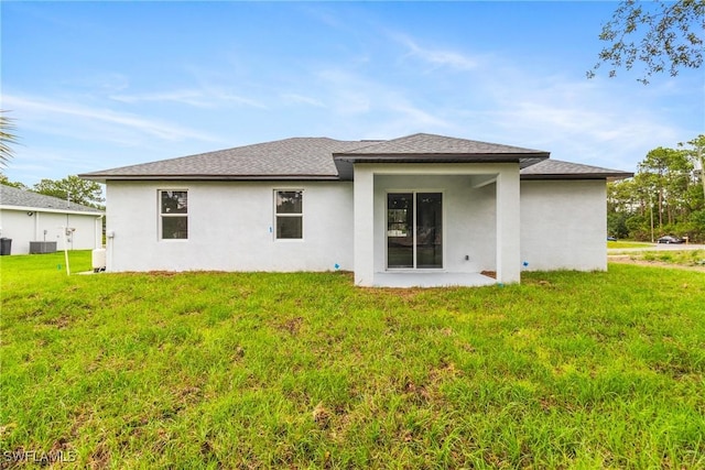2605 Darlene Pl, Lehigh Acres, FL 33971 - rear view of house featuring stucco siding, a lawn, roof with shingles, and central air condition unit