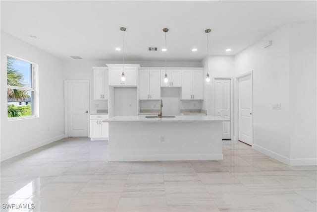 2605 Darlene Pl, Lehigh Acres, FL 33971 - kitchen with a sink, white cabinetry, an island with sink, baseboards, and light countertops