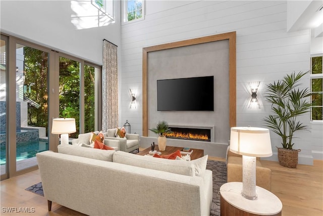 845 11th Ave S, Naples, FL 34102 - living room with wood finished floors, healthy amount of natural light, a lit fireplace, wood walls, and a high ceiling
