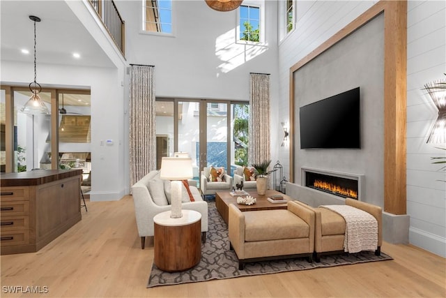 845 11th Ave S, Naples, FL 34102 - living area with light wood-type flooring, a lit fireplace, baseboards, and a towering ceiling