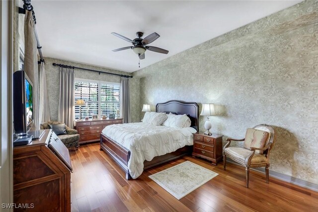 23159 Amgci Way Unit 302, Estero, FL 33928 - bedroom featuring wallpapered walls, wood finished floors, a ceiling fan, and baseboards
