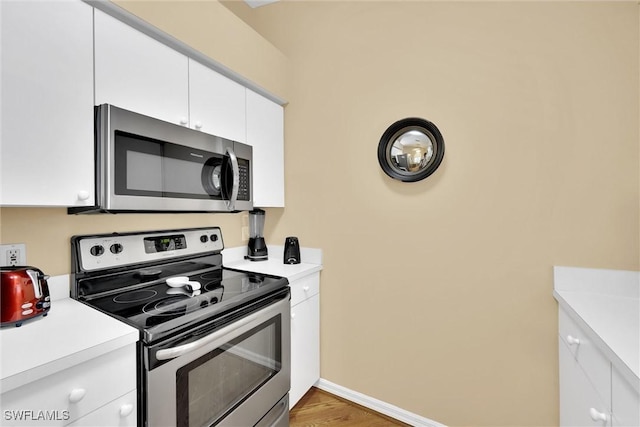 291 Mango St, Fort Myers Beach, FL 33931 - kitchen with appliances with stainless steel finishes, light countertops, white cabinets, and light wood-style floors