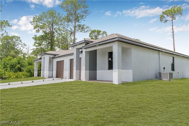 452/454 Loretta Ave S, Lehigh Acres, FL 33974 - view of side of home with a yard, stucco siding, an attached garage, and central AC unit