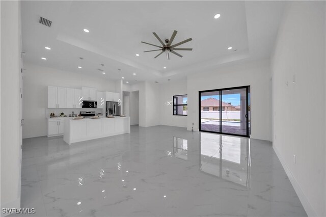 139 SE 2nd Ave, Cape Coral, FL 33990 - unfurnished living room with a tray ceiling, light marble finish floors, a ceiling fan, recessed lighting, and baseboards