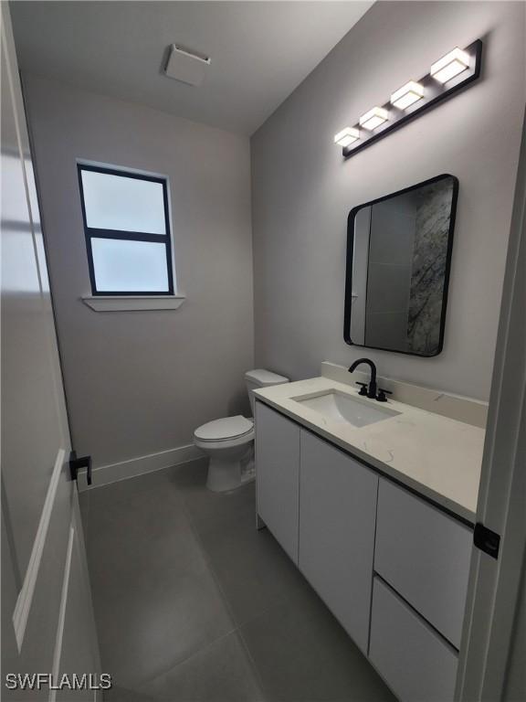 3279 31st Ave NE, Naples, FL 34120 - half bathroom with vanity, toilet, tile patterned floors, and baseboards