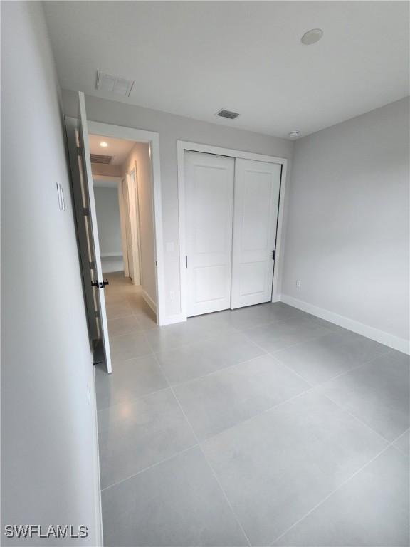 3279 31st Ave NE, Naples, FL 34120 - unfurnished bedroom with tile patterned floors, a closet, and baseboards
