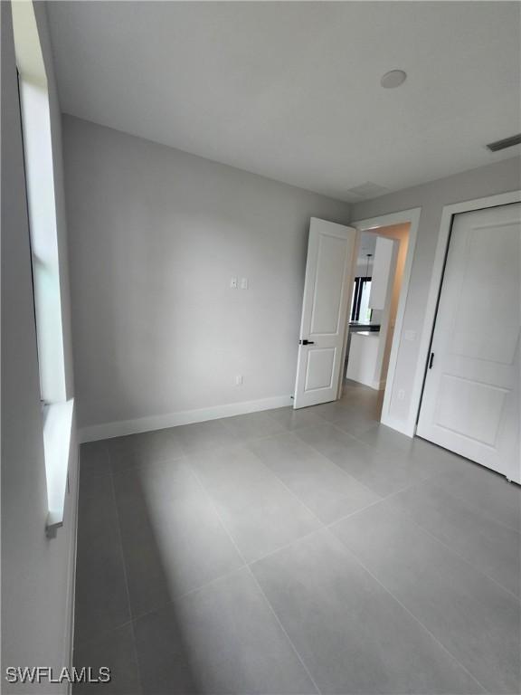 3279 31st Ave NE, Naples, FL 34120 - unfurnished bedroom featuring baseboards, tile patterned flooring, and a closet