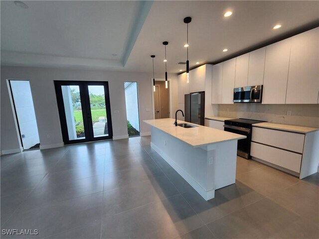 3279 31st Ave NE, Naples, FL 34120 - kitchen with stainless steel appliances, a sink, white cabinets, light countertops, and a center island with sink