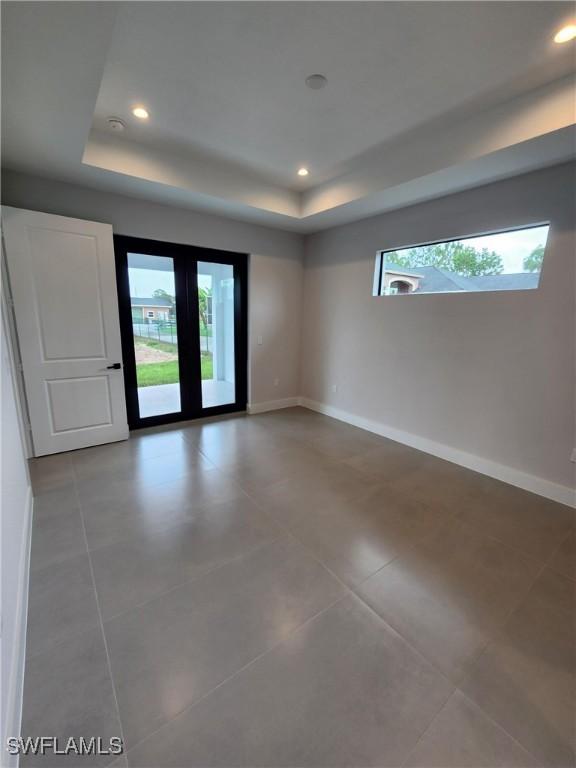 3279 31st Ave NE, Naples, FL 34120 - tiled spare room with a tray ceiling, plenty of natural light, baseboards, and recessed lighting