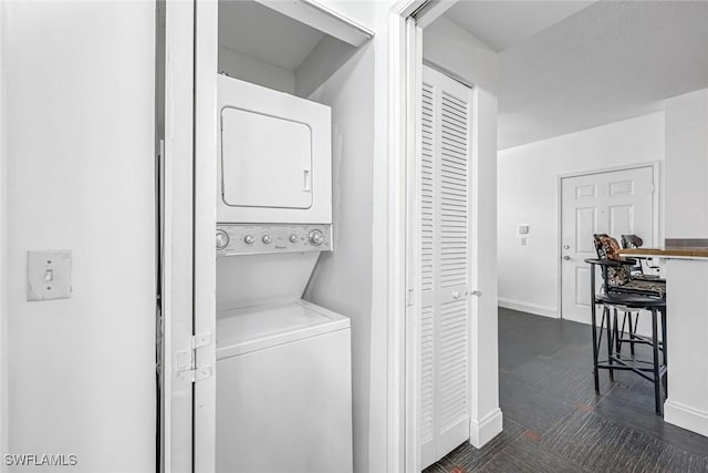 1220 Reserve Way Unit 107, Naples, FL 34105 - laundry area with stacked washer / dryer and baseboards