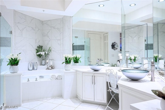 133 Colonade Cir, Naples, FL 34103 - bathroom with two vanities, a bath, tile walls, marble finish flooring, and a shower with door