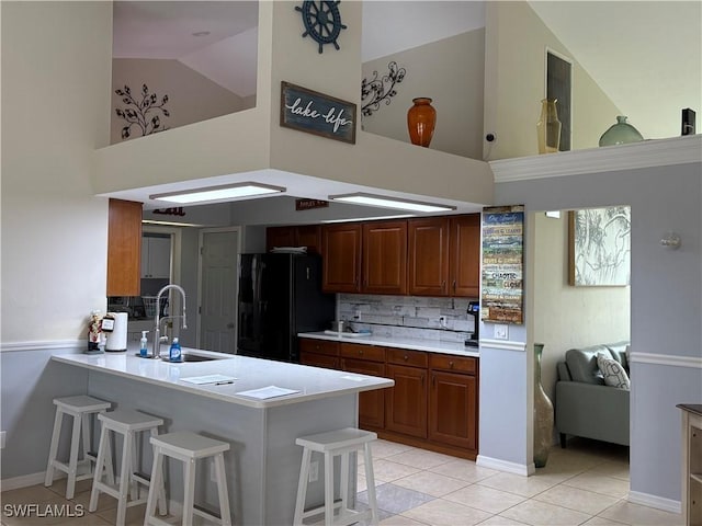 1118 Grove Dr, Naples, FL 34120 - kitchen with high vaulted ceiling, black refrigerator with ice dispenser, light countertops, a peninsula, and light tile patterned floors