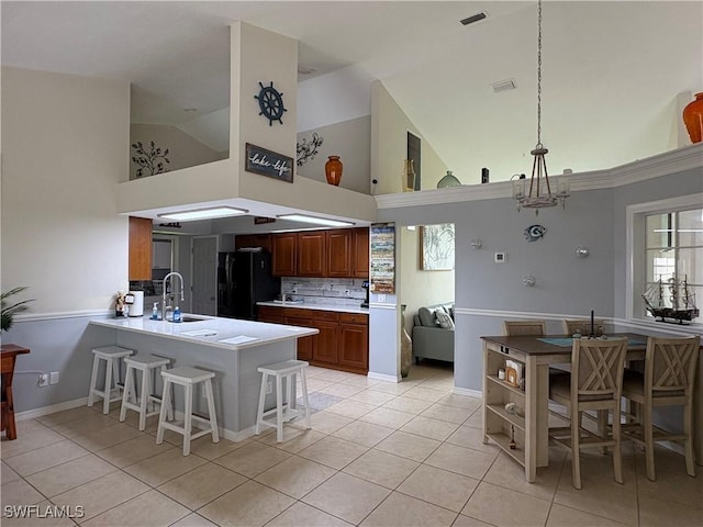 1118 Grove Dr, Naples, FL 34120 - kitchen with freestanding refrigerator, high vaulted ceiling, a peninsula, light tile patterned floors, and a breakfast bar