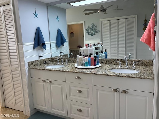 1118 Grove Dr, Naples, FL 34120 - bathroom featuring a closet, double vanity, ceiling fan, a wainscoted wall, and tile patterned flooring