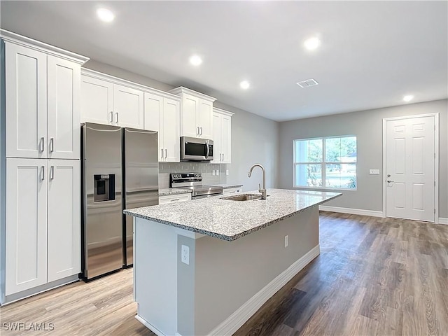 3307 55th St W, Lehigh Acres, FL 33971 - kitchen with appliances with stainless steel finishes, a sink, a center island with sink, light wood-style floors, and white cabinets