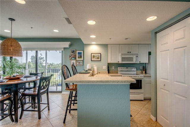 16641 Stringfellow Rd Unit 506, Bokeelia, FL 33922 - kitchen featuring white appliances, light tile patterned floors, white cabinetry, a breakfast bar area, and recessed lighting