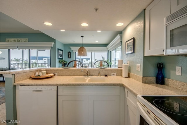 16641 Stringfellow Rd Unit 506, Bokeelia, FL 33922 - kitchen with white appliances, a sink, white cabinets, a peninsula, and light countertops