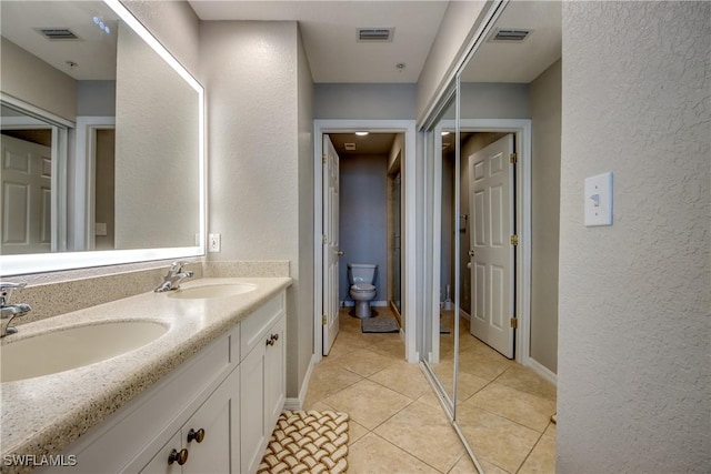 16641 Stringfellow Rd Unit 506, Bokeelia, FL 33922 - full bathroom with double vanity, toilet, a textured wall, tile patterned flooring, and baseboards