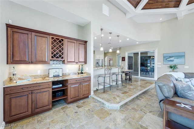 1658 Mcilvaine Ct, Marco Island, FL 34145 - bar area featuring stone tile flooring, beamed ceiling, baseboards, a towering ceiling, and hanging light fixtures