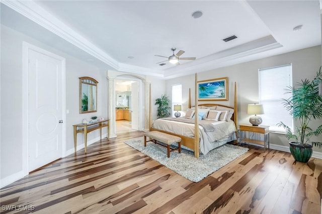 1658 Mcilvaine Ct, Marco Island, FL 34145 - bedroom featuring a tray ceiling, decorative columns, wood finished floors, baseboards, and arched walkways