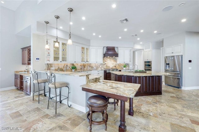 1658 Mcilvaine Ct, Marco Island, FL 34145 - kitchen featuring appliances with stainless steel finishes, custom exhaust hood, stone tile flooring, baseboards, and decorative backsplash